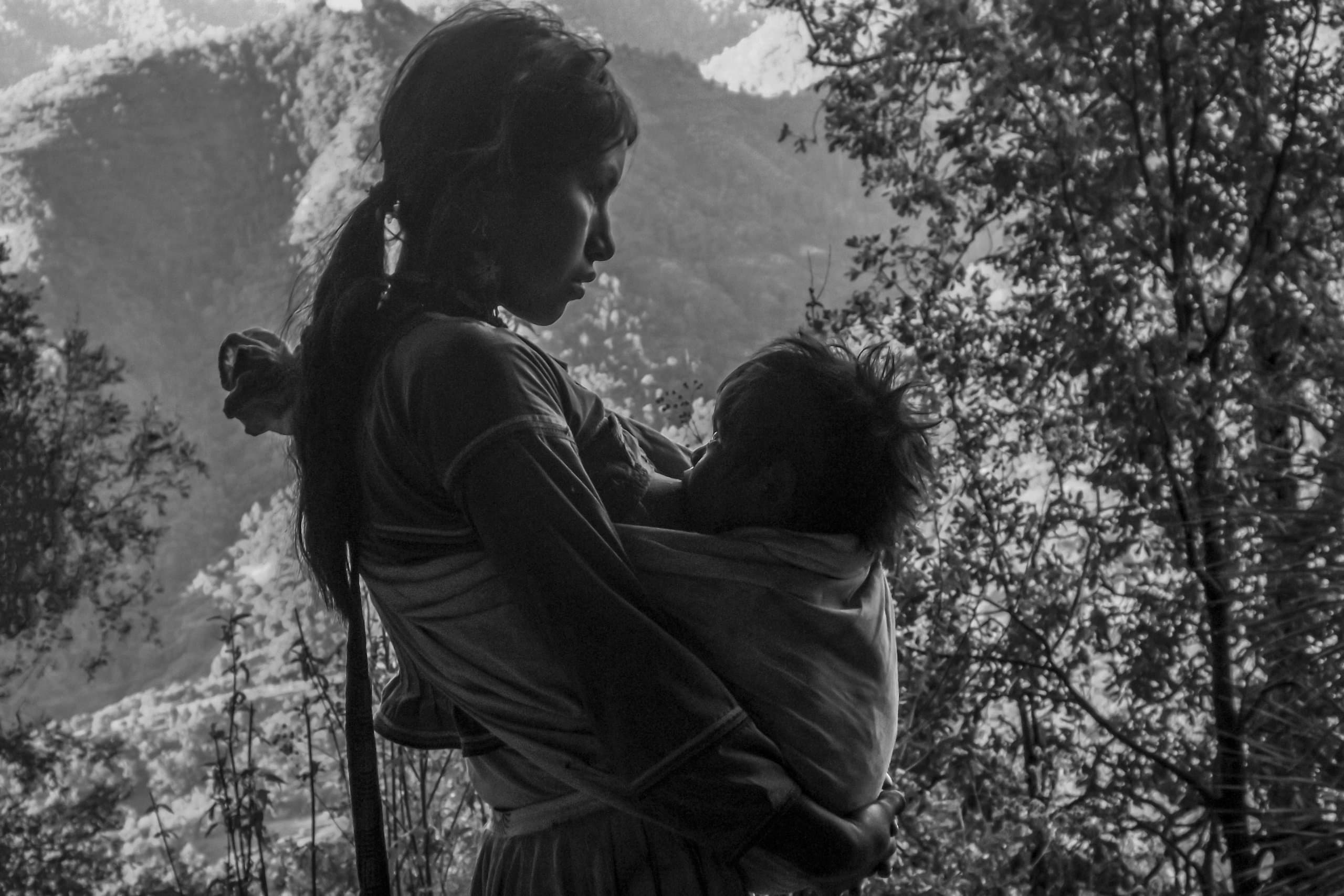 Madre cargando a su hijo frente a la sierra — fotografía documental